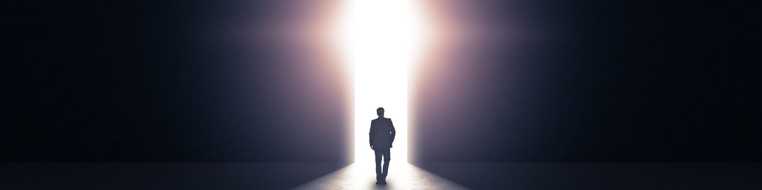 Mann tritt durch eine Tür aus der Dunkelheit hinaus ins Licht.