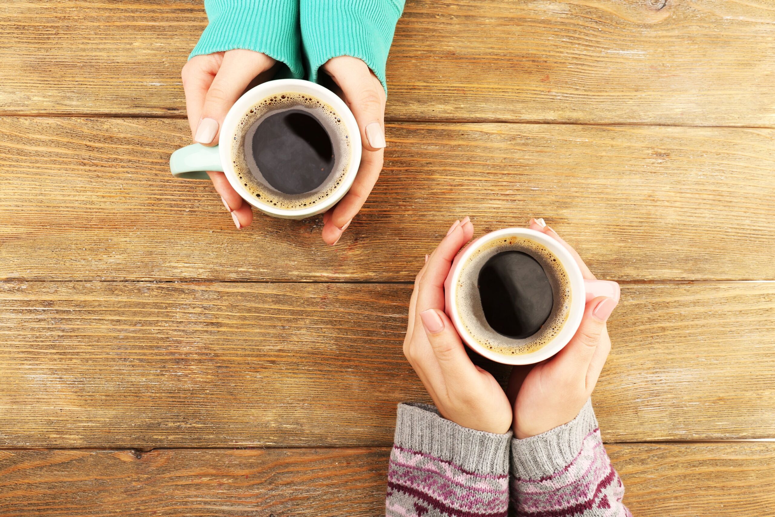 Hände halten Kaffeetassen.