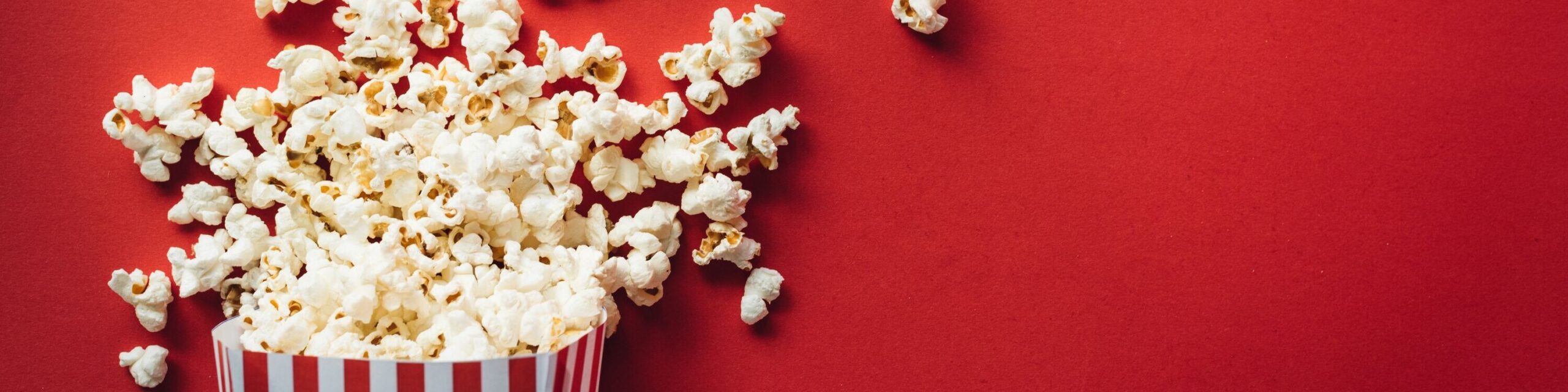 Tüte Popcorn vor rotem Hintergrund